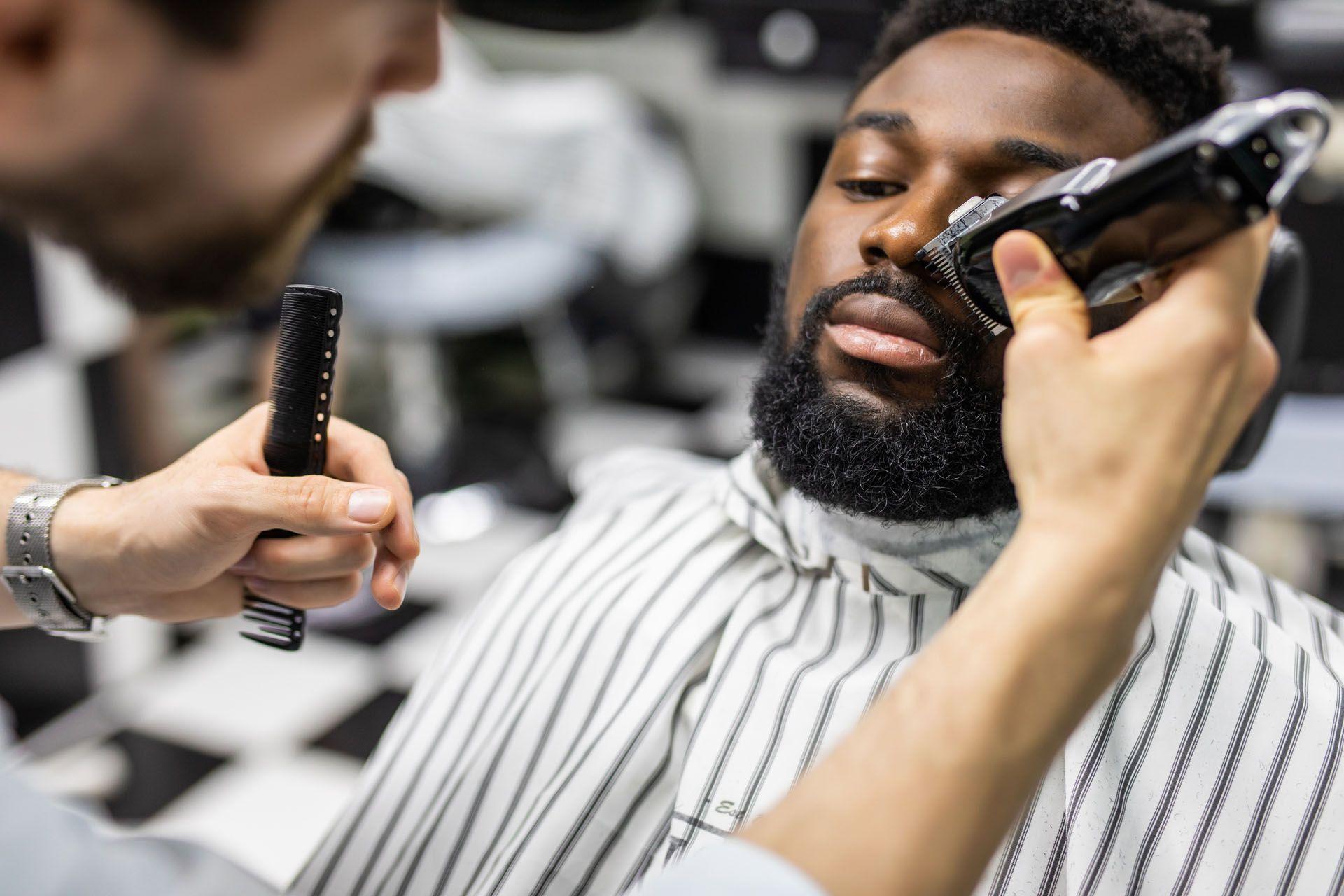 Un barbier entrain de raser la barbe de son client