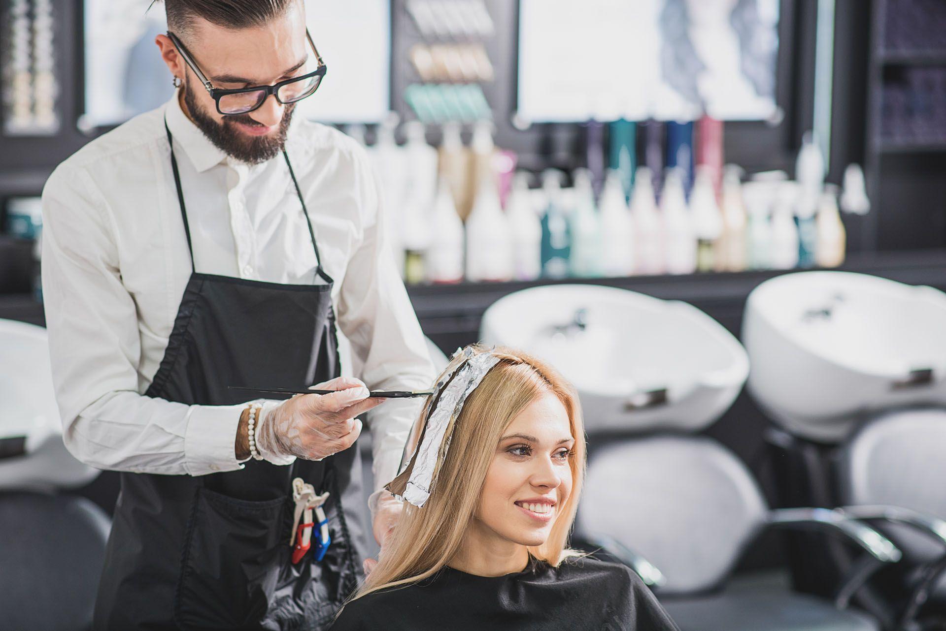 Un coiffeur entrain d'appliquer une coloration à sa cliente