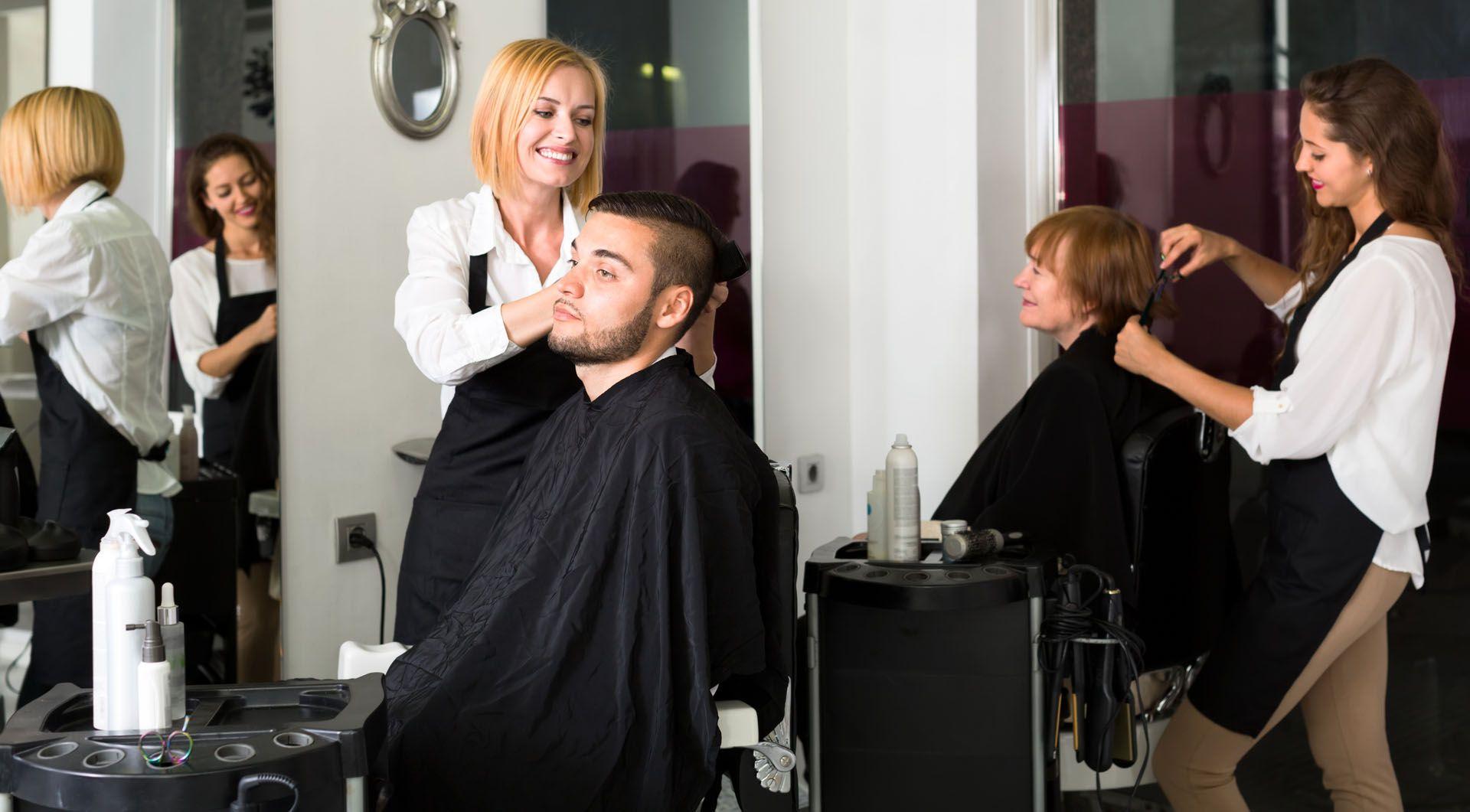 Une coiffeuse entrain de réaliser un brushing à son client