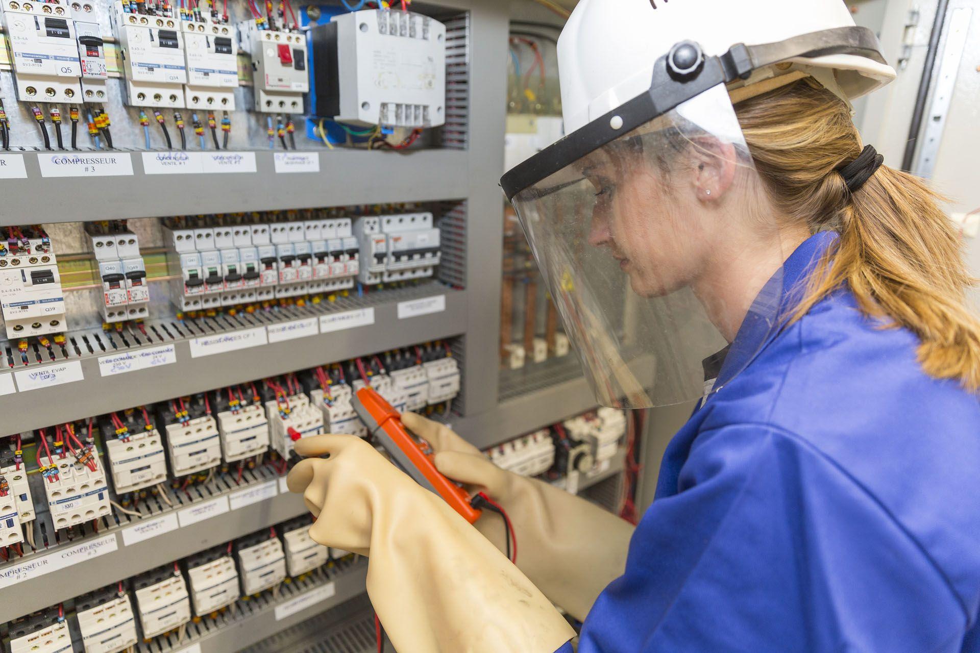 Une électricienne devant un tableau éléctrique